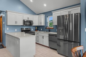 Une cuisine moderne avec des meubles blancs, des appareils en acier inoxydable et un îlot central.