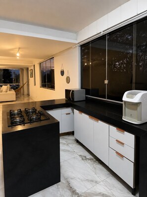 Una cocina moderna con una isla central, encimera negra, armarios blancos y un ventanal grande.