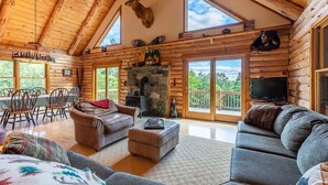 A log cabin interior with a stone fireplace, wooden furniture, and a mounted deer head. - Log Cabin Retreat on Private Vermont Estate (Reading)