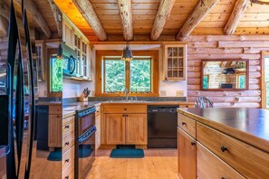 Eine Holzblockhausküche mit Holzausstattung, einem Geschirrspüler und einem großen Fenster.
