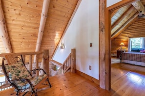 Ein Holzkamin mit schrägverdeckter Decke, einer Treppe und einem Bett mit gemustertem Überwurf.