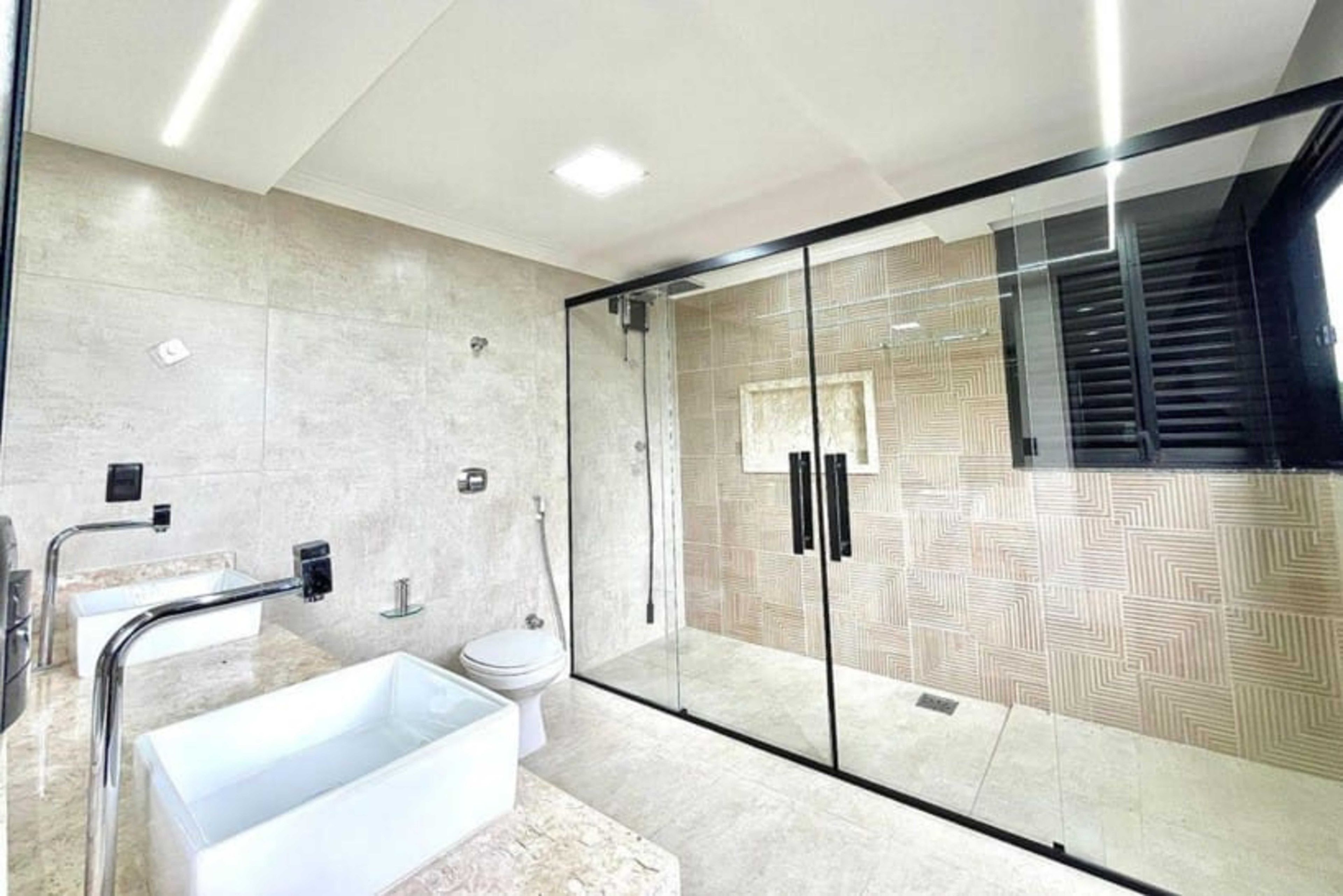 A modern bathroom with a glass shower enclosure, a freestanding bathtub, and a toilet.