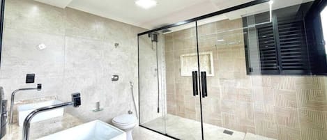 A modern bathroom with a glass shower enclosure, a freestanding bathtub, and a toilet.