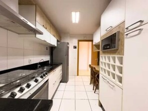 A modern kitchen with a gas stove, refrigerator, and white cabinets.