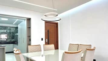 A modern dining area with a glass-top table and cushioned chairs.