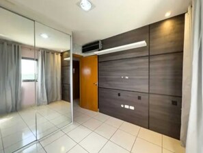 A room with a glass partition, a wooden wardrobe, and a tiled floor.