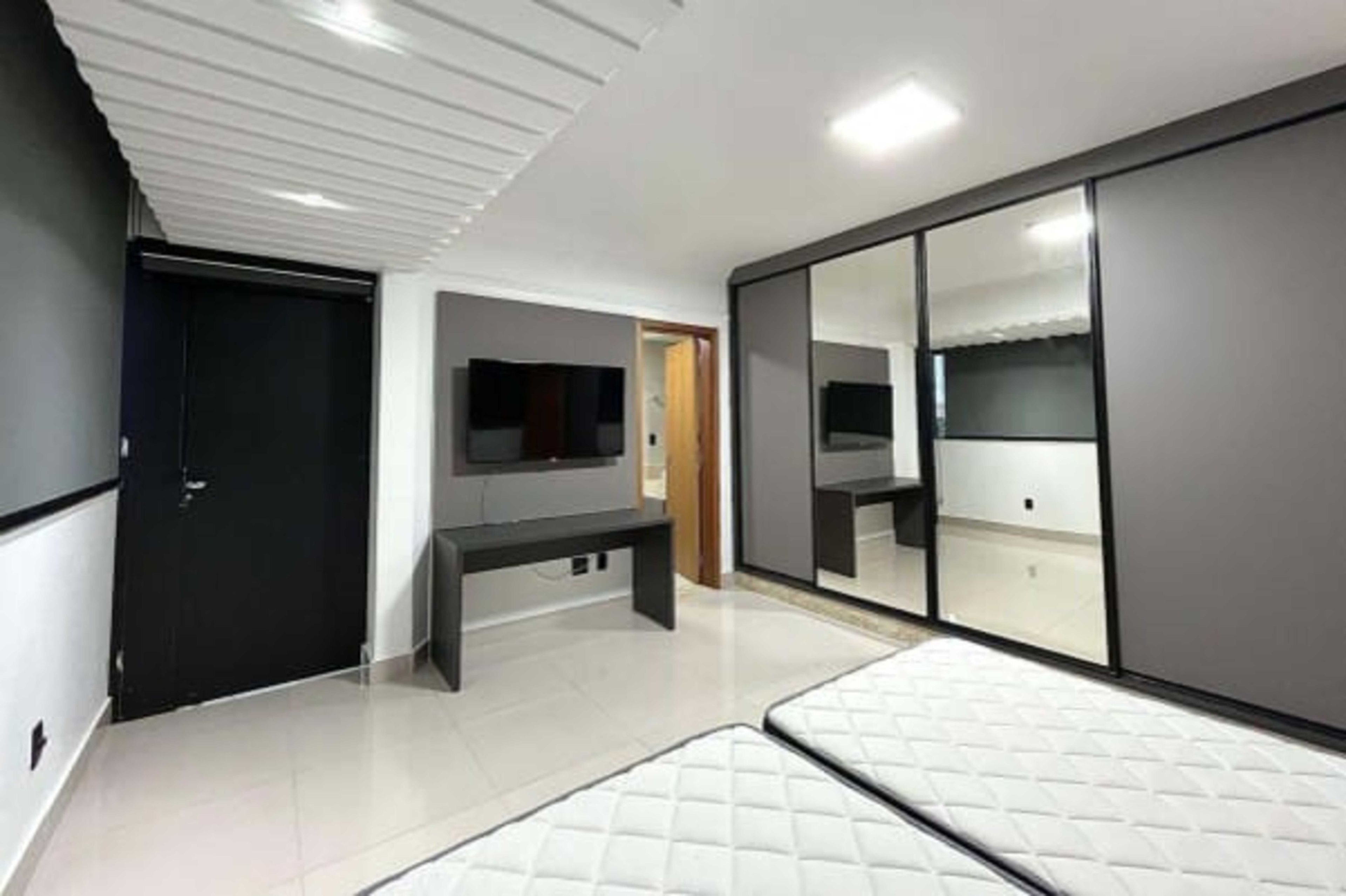 A modern bedroom with a bed, a TV, and a wardrobe.