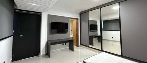 A modern bedroom with a bed, a TV, and a wardrobe.