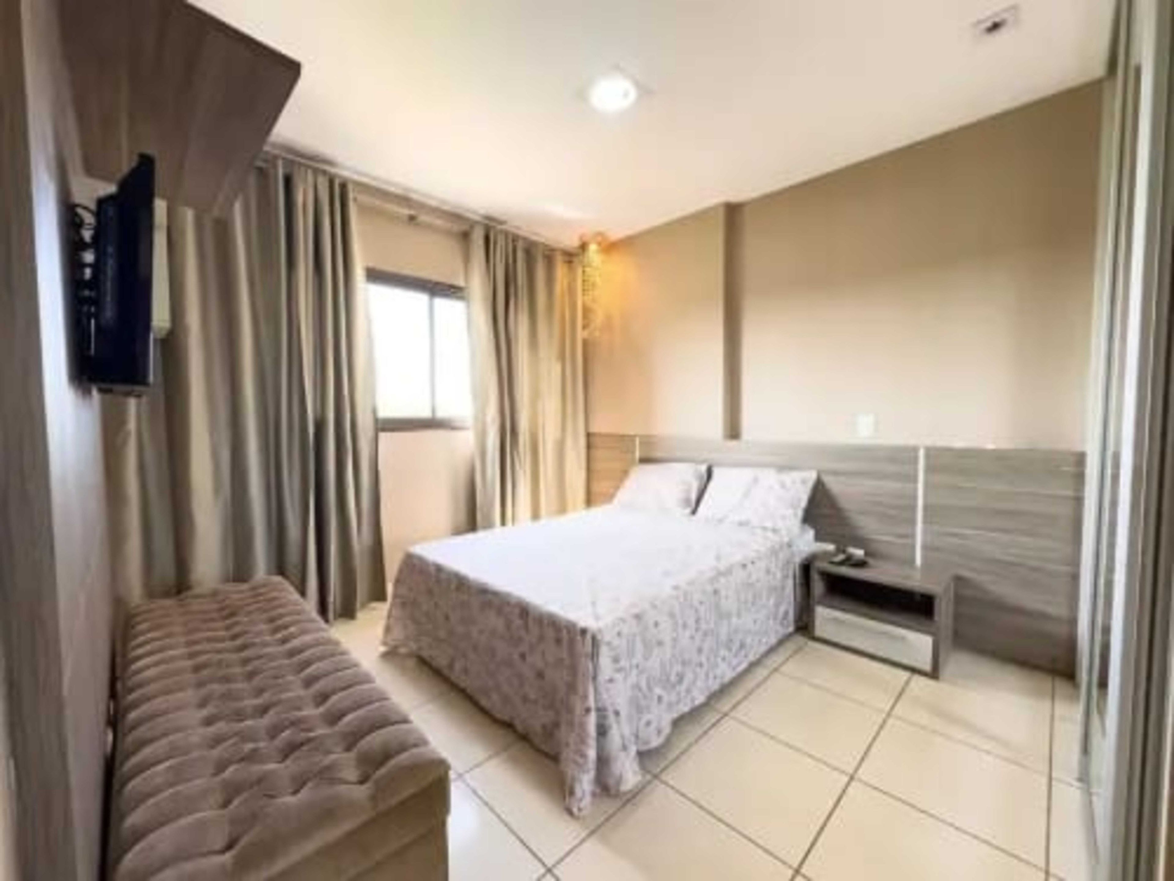 A bedroom with a bed, bedside table, and a bench.