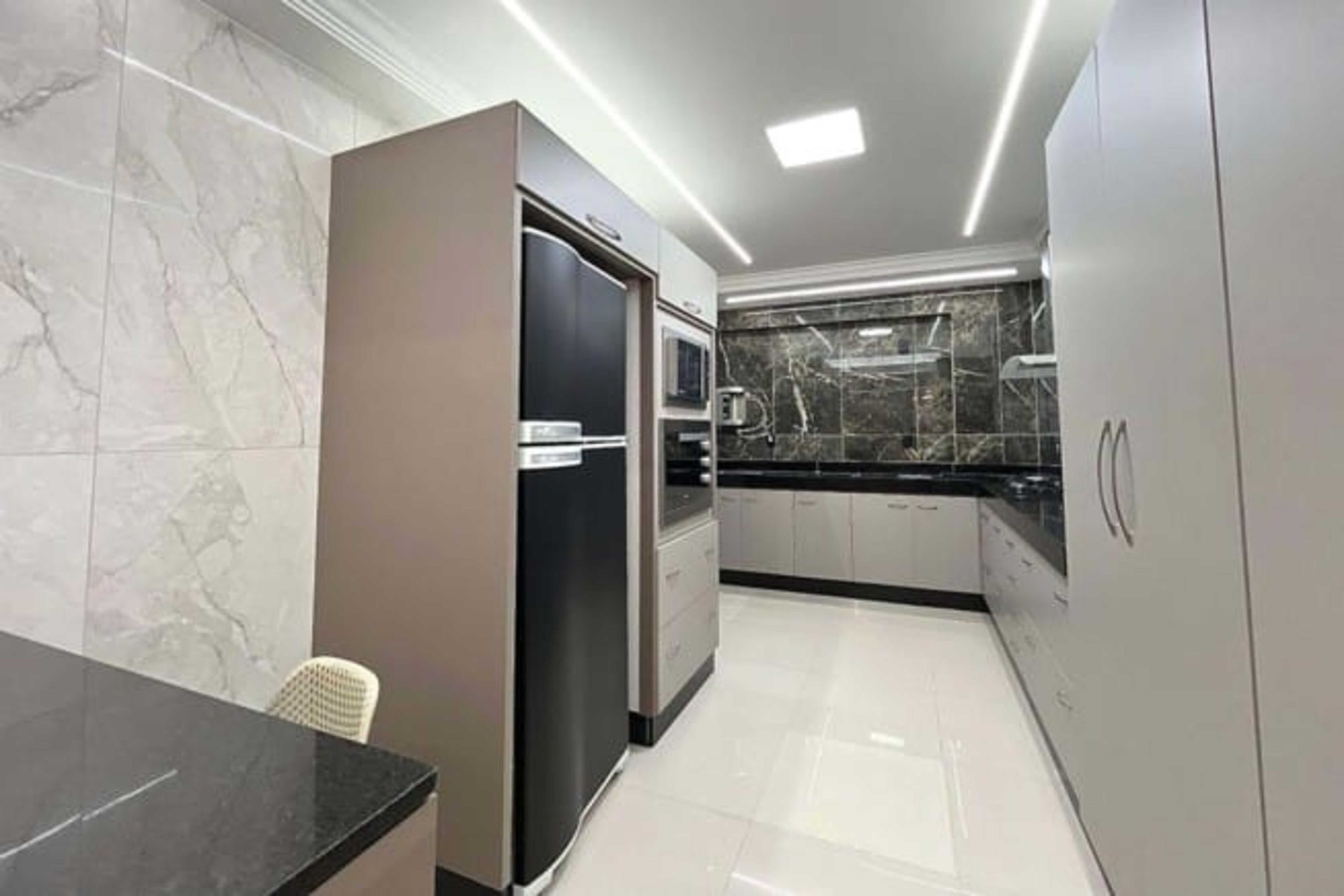 A modern kitchen with marble walls, stainless steel appliances, and a black countertop.