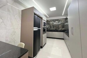 A modern kitchen with marble walls, stainless steel appliances, and a black countertop.
