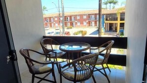 A balcony with a table and chairs, a view of buildings, and a tiled floor. - Residencial Jardins Taperapuan (Porto Seguro)