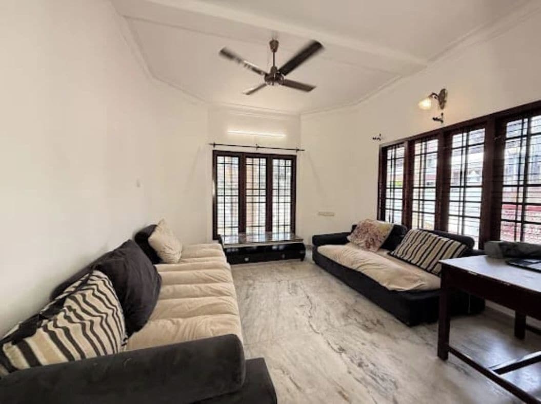 A living room with a sofa set, a table, and a ceiling fan.