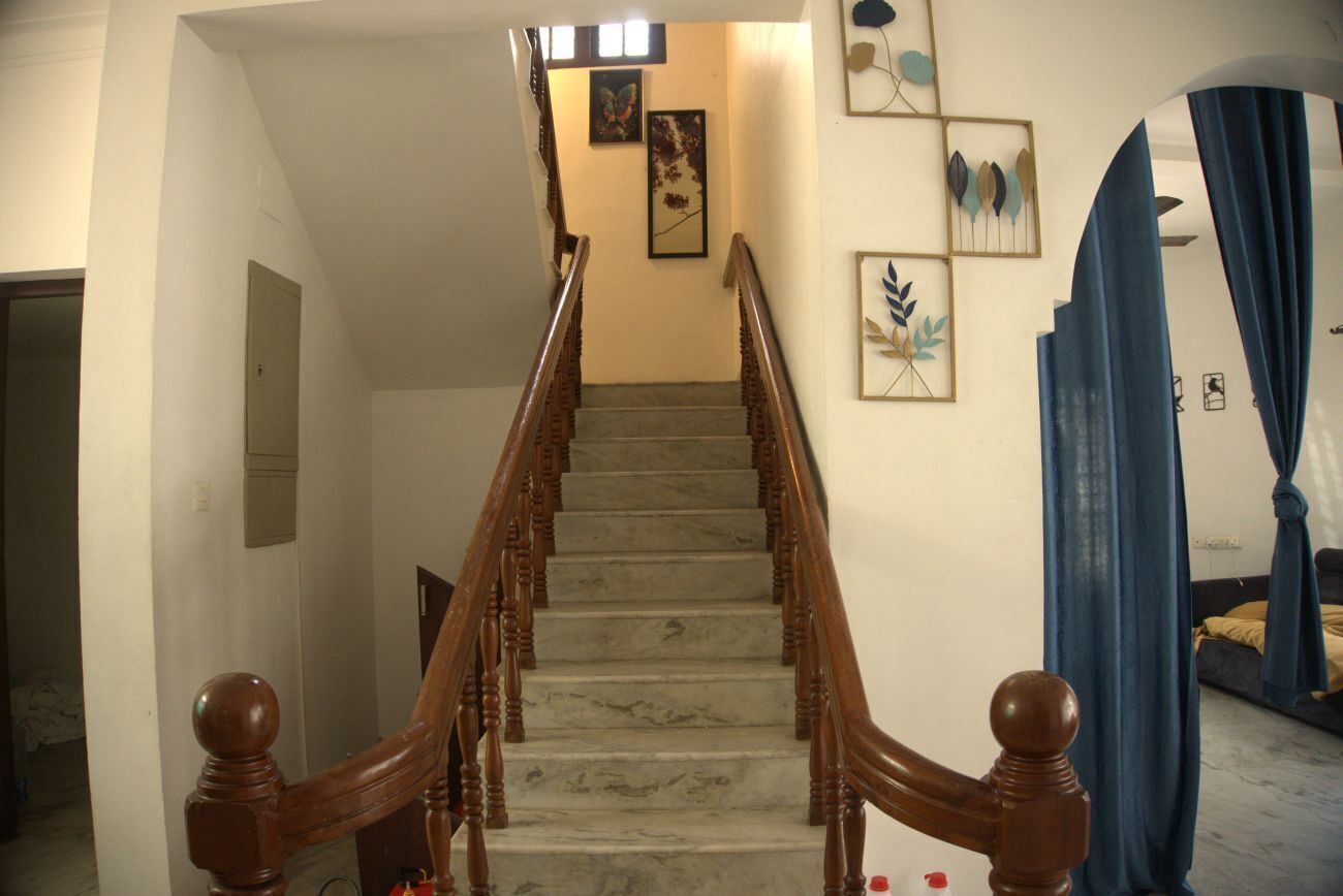A staircase with wooden balusters, a marble floor, and wall art.
