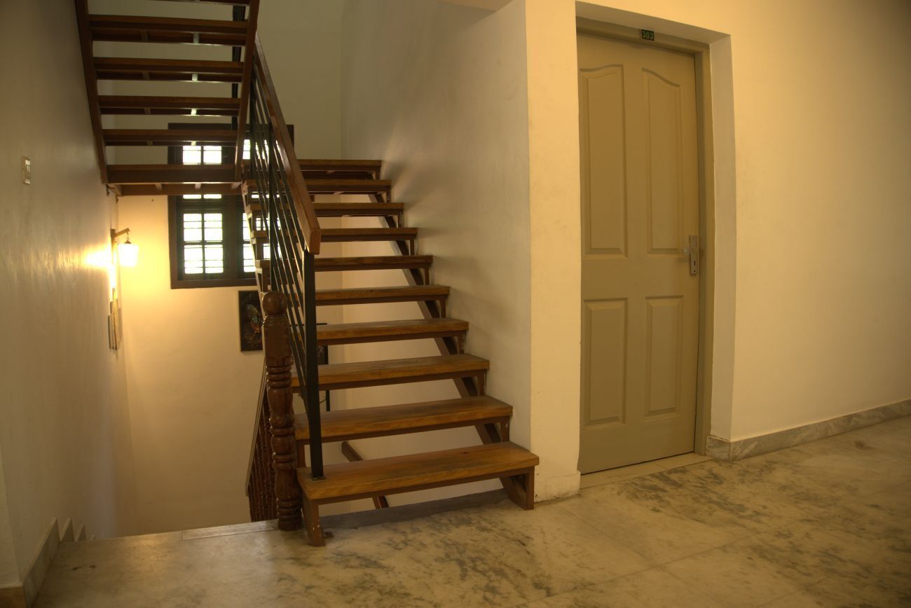 A wooden staircase with a handrail, a light fixture on the wall, and a closed door.
