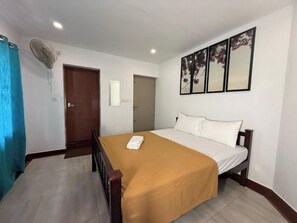 Une chambre d’hôtel avec un lit, un ventilateur, une porte et une œuvre d’art accrochée au mur.