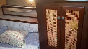 A room with a bed, a wooden wardrobe with a perforated door, and a window with a view of the outside. - Seattle Floating Cabin Experience 40-Ft Boat-Yacht Cruiser (Seattle)