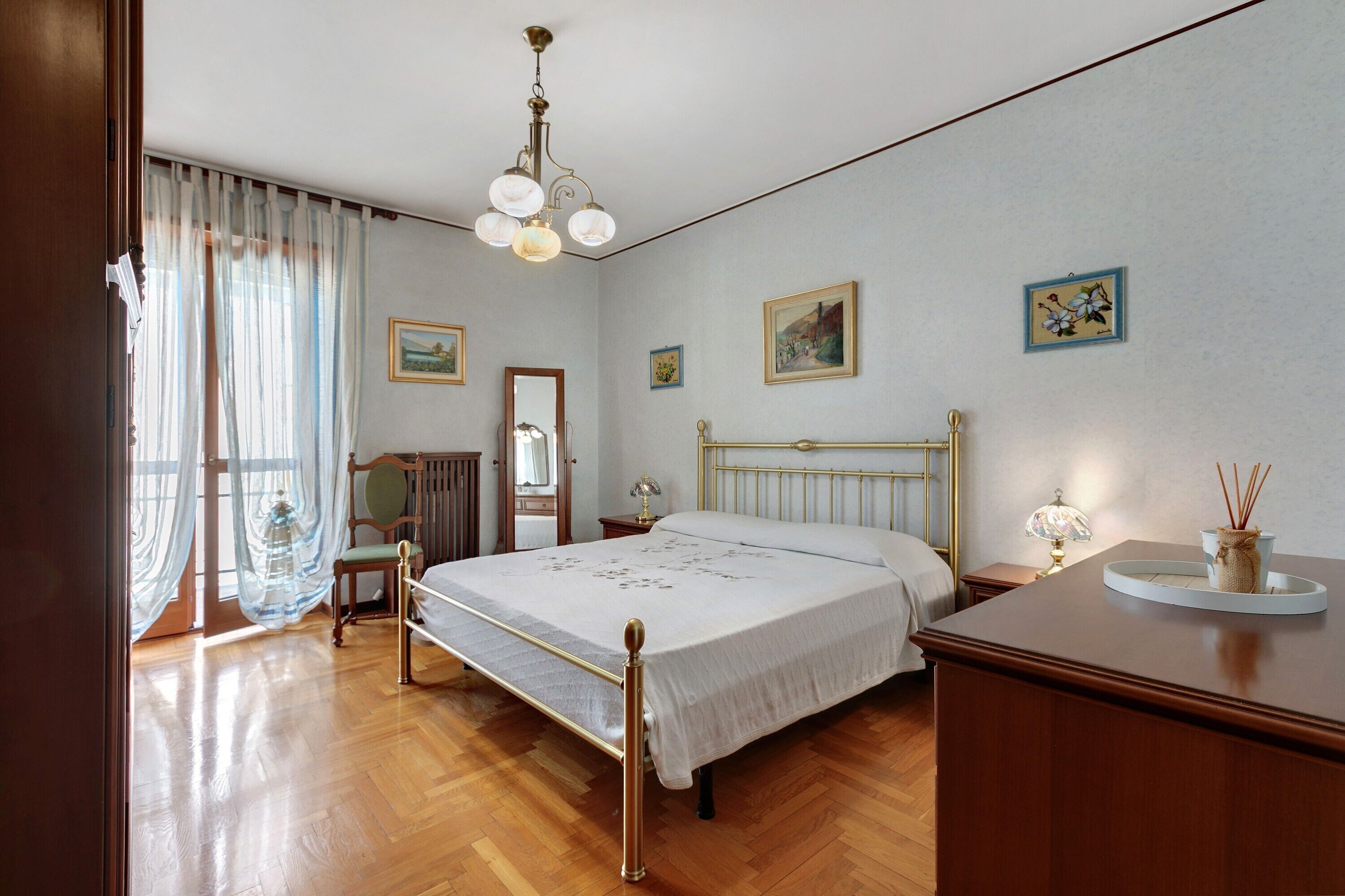 Une chambre d’hôtel avec un lit, une table de chevet, un miroir et une fenêtre avec des rideaux.