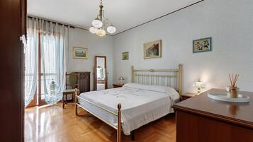 Une chambre d’hôtel avec un lit, une table de chevet, un miroir et une fenêtre avec des rideaux.