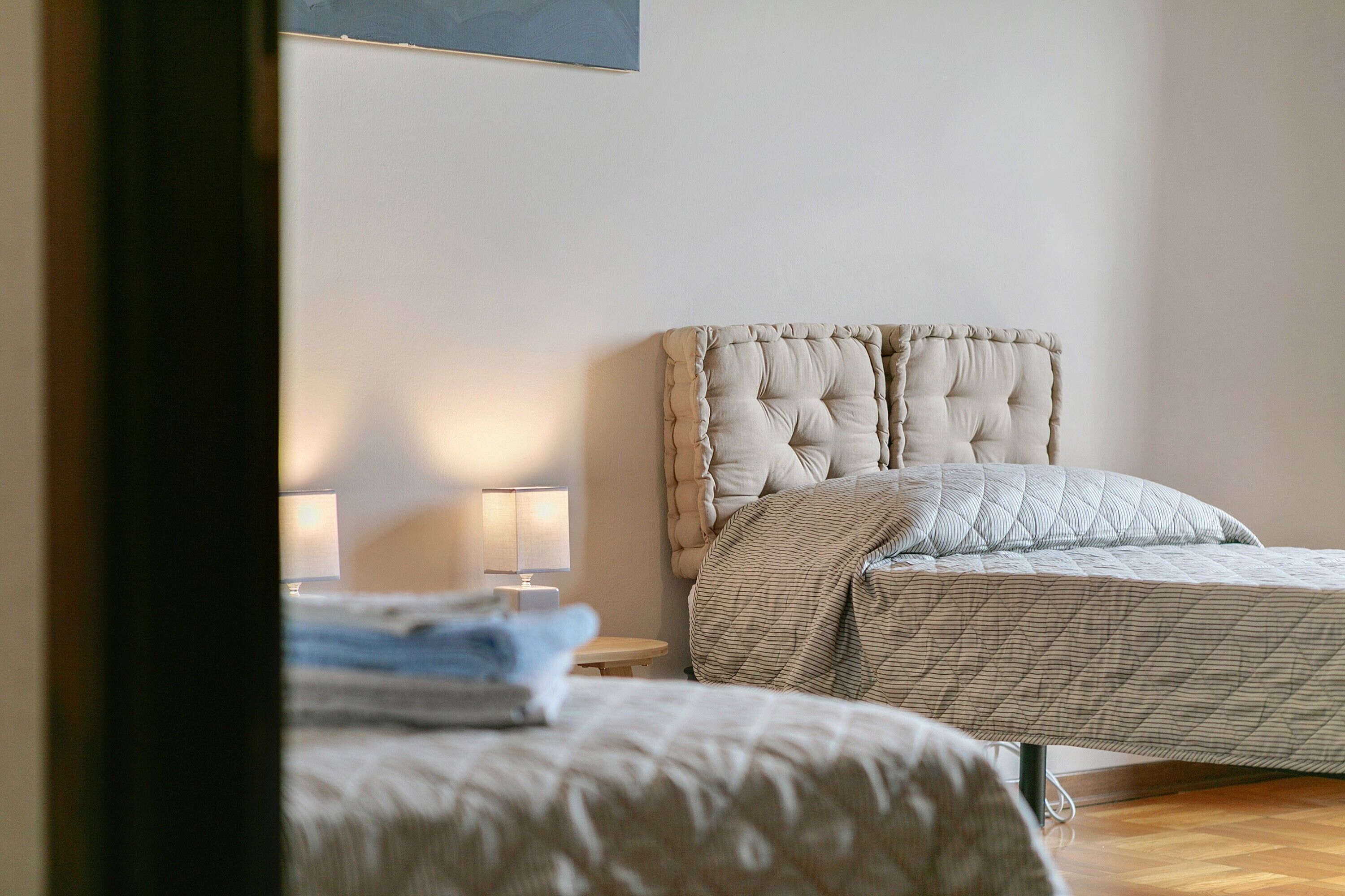 Un dormitorio con cama, mesita de noche y lámpara.