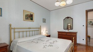 Une chambre à coucher avec un lit, une commode, un miroir et une œuvre d’art accrochée au mur.