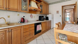 Une cuisine dotée de meubles en bois, d’un évier, d’une cuisinière et d’un coin repas avec une table et des chaises.
