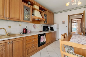 Une cuisine dotée de meubles en bois, d’un évier, d’une cuisinière et d’un coin repas avec une table et des chaises.