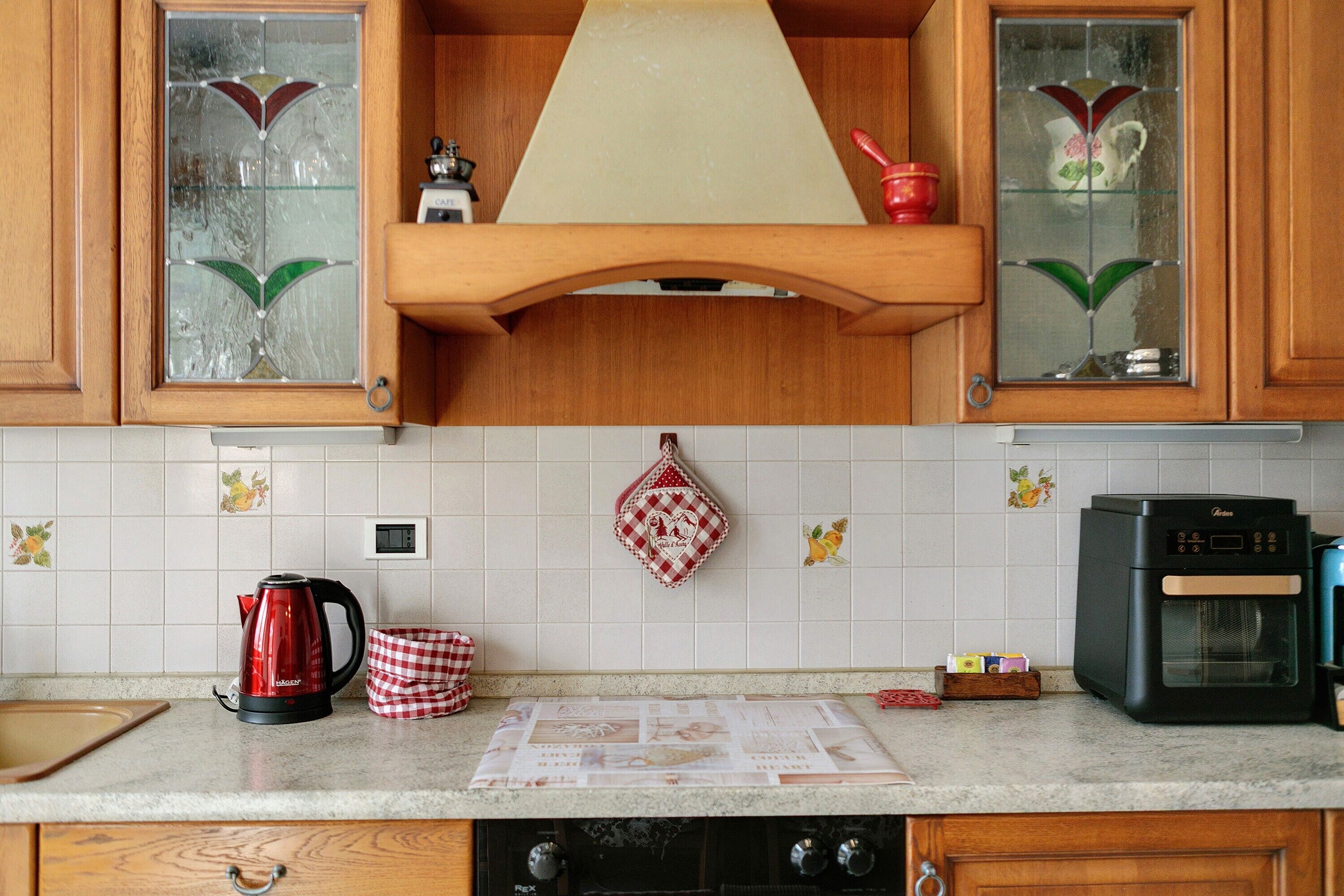 Una cocina con armarios de madera, cafetera, hervidor y microondas.