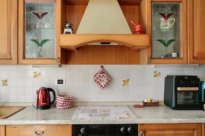 Una cocina con armarios de madera, cafetera, hervidor y microondas.