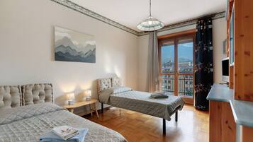 Una habitación de hotel con dos camas, un cuadro, una ventana con vistas y un armario de madera.