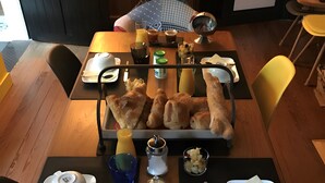 Ruokapöytä on katettu erilaisilla tarjoiluastioilla, kuten leivällä, mausteilla ja teekannulla.