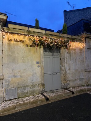 Eine Gebäudefassade mit einer Steinwand, einer Metalttür und einem Schild mit der Aufschrift 'La Maison de Yann'.