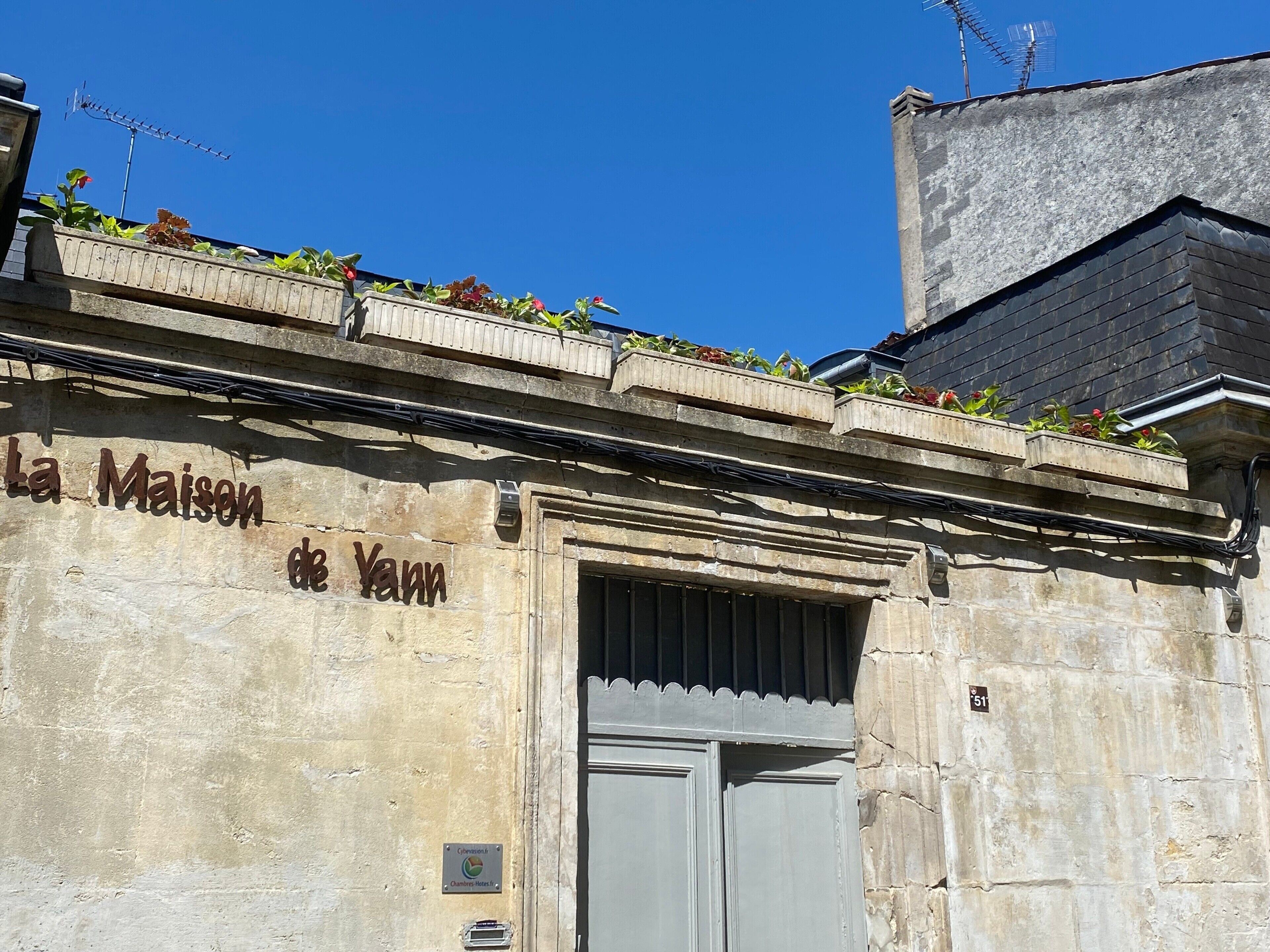Un bâtiment sur lequel on peut lire l’inscription « La Maison de Yann », et une porte dotée d’une poignée en métal.