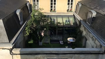Une cour dotée d’un toit de verre, entourée d’immeubles aux façades en briques et aux nombreuses fenêtres.