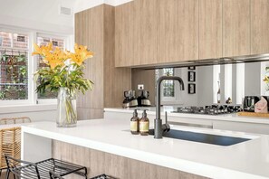 Eine moderne Küche mit weißer Arbeitsplatte, einem Edelstahl-Spülbecken und einer Vase mit Blumen.