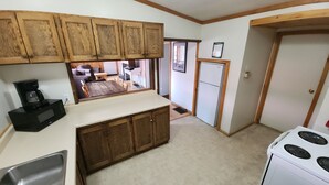 A compact kitchen with wooden cabinets, a microwave, a stove, and a refrigerator.