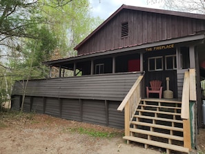 Un bâtiment rustique en bois, portant l’inscription « La cheminée », avec un escalier en bois menant à une véranda.