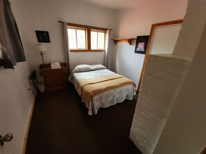 Ein Schlafzimmer mit einem Bett, einem Nachttisch, einer Lampe und einem Fenster.