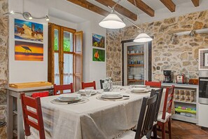 Comedor con pared de piedra, vigas de madera y una mesa preparada para cuatro.