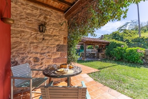 A stone wall with a hanging lantern, a wooden bench, and a table with a basket of fruit and a cup. - Rural house 'Del Tesoro "Tesoro Pequeño"' with mountain views, balcony, and Wi-Fi (Triongo)