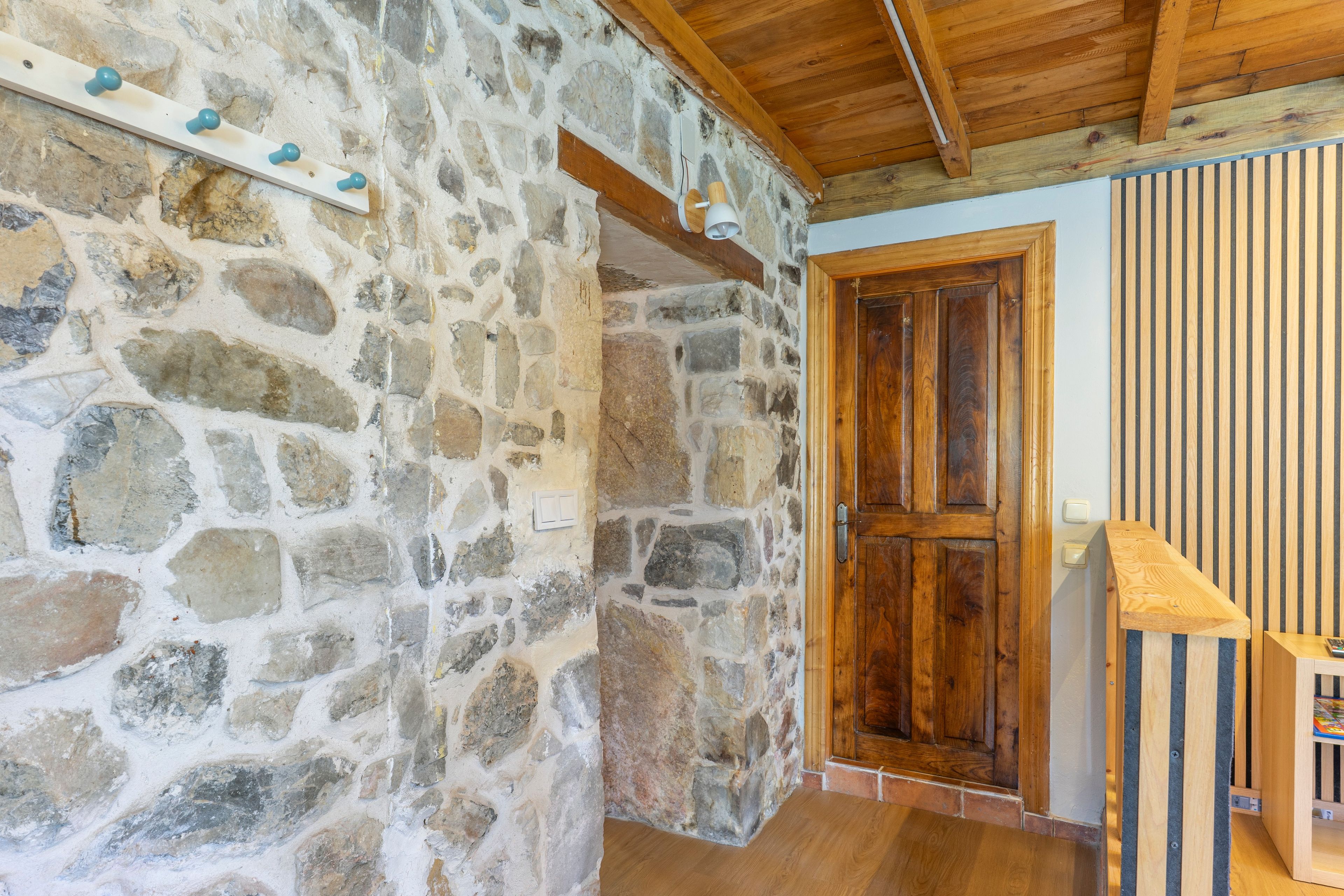 Paredes de pedra com porta e escada de madeira.