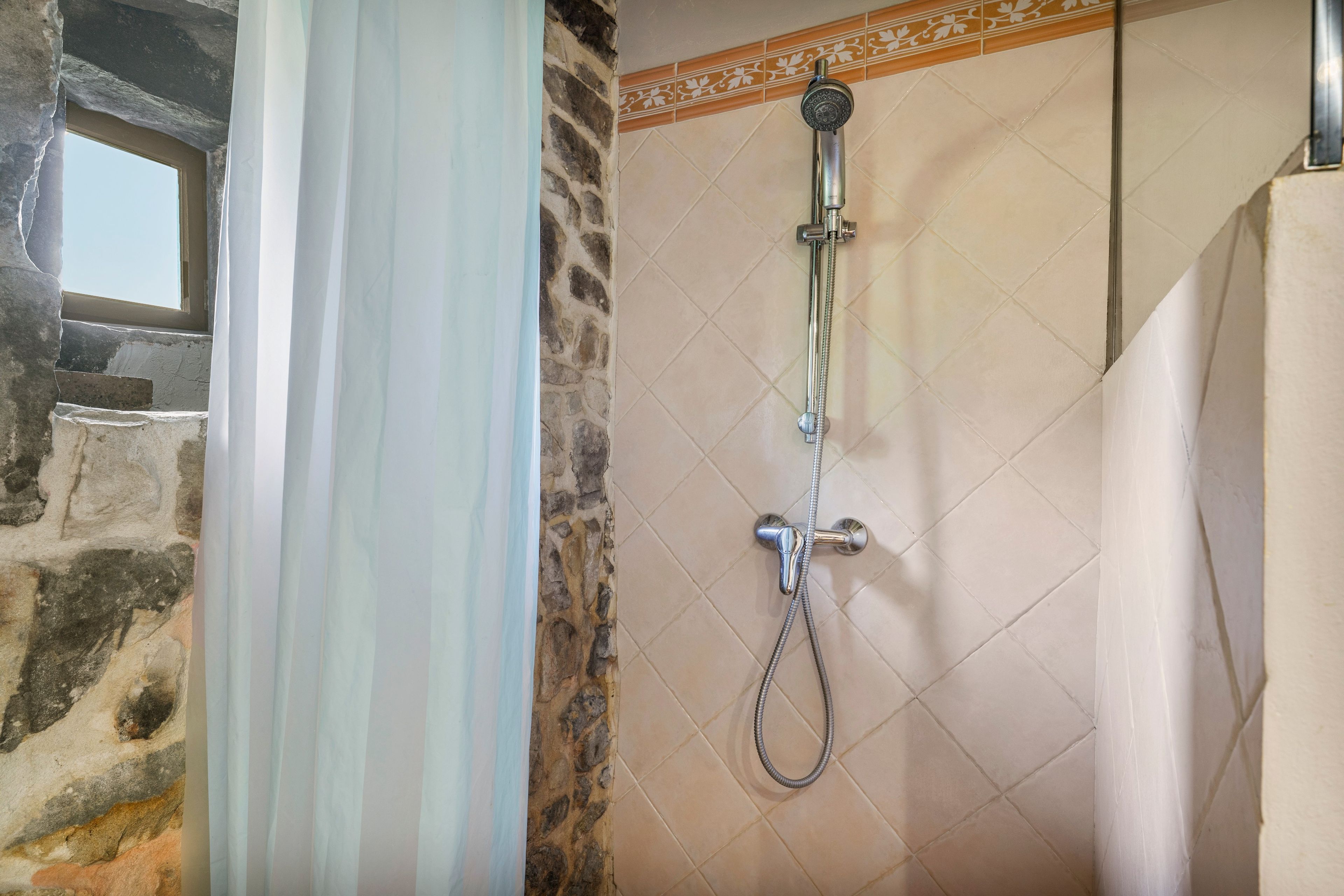 A shower with a handheld showerhead and a wall-mounted faucet.