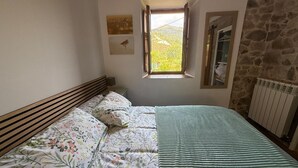 Ein Schlafzimmer mit einem Bett, einem Fenster, einer Steinsäule und einer Heizung.