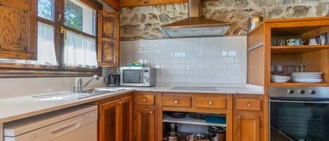 Una cocina con armarios de madera, horno empotrado, microondas y lavavajillas.