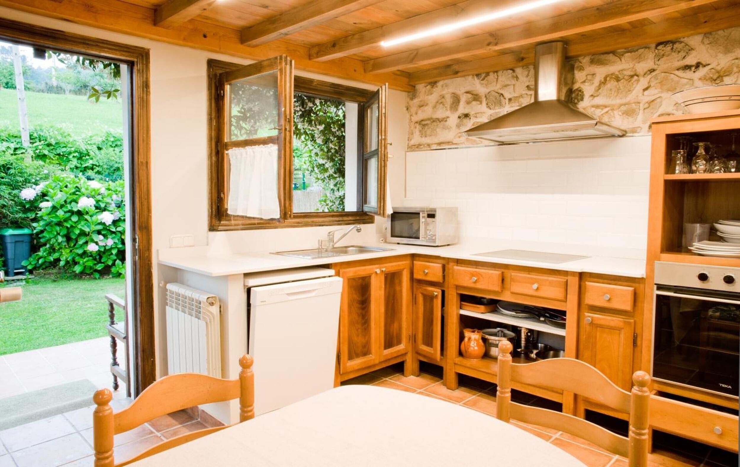 Una cocina con armarios de madera, microondas y lavavajillas.