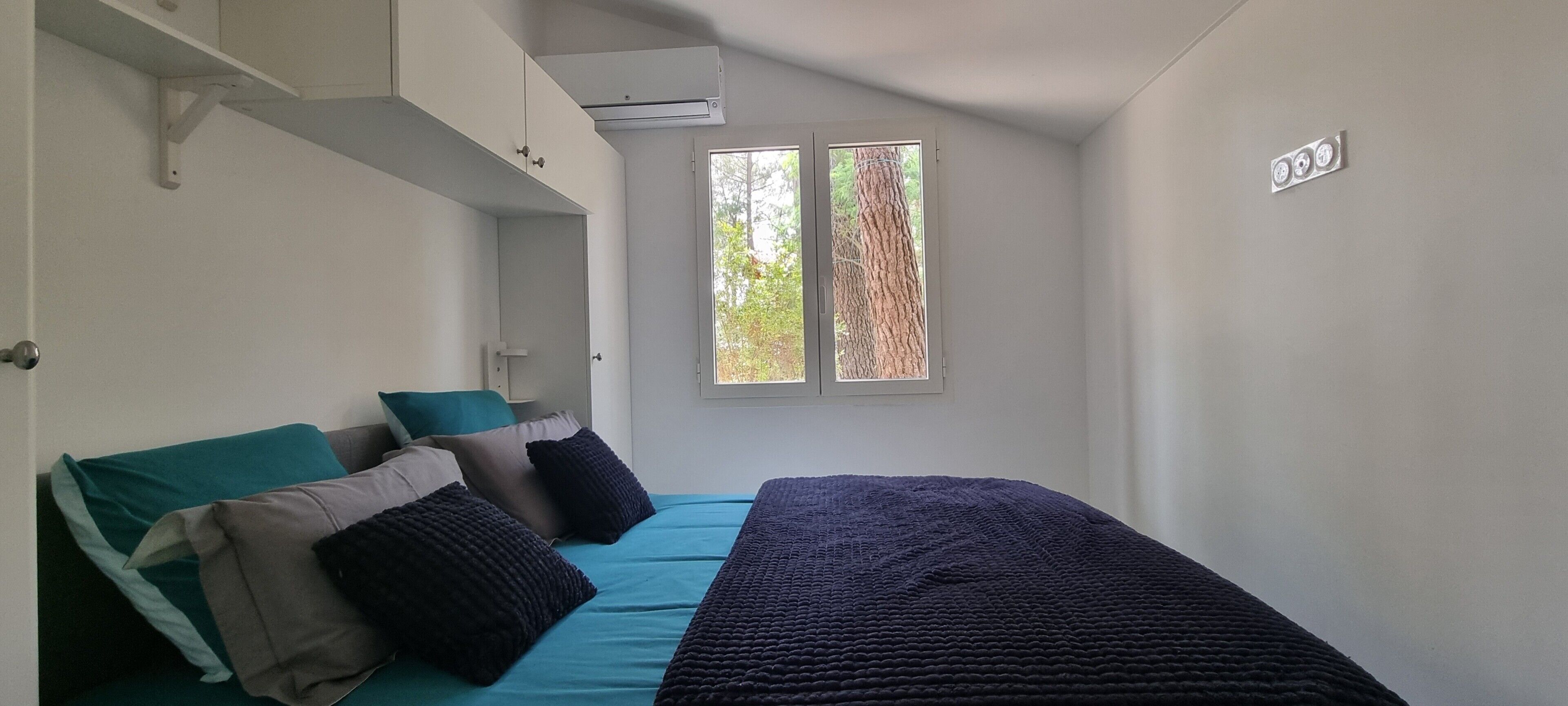 Un dormitorio con cama, almohadas, ventana y puerta.