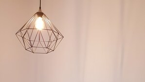 Sänky, jossa on geometrisesti kuvioitu pääty, turkoosi, tikattu päiväpeite ja kaksi tyynyä.