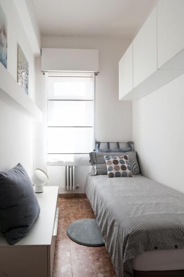 A compact bedroom with a bed, a desk, and a window. - Fly by Suites Pescara (Pescara)