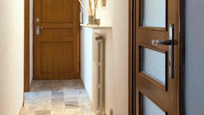 A hallway with a wooden door, a radiator, and a wall-mounted air conditioning unit. - Fly by Suites Pescara (Pescara)