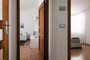 A modern interior with a white sofa, a small table, and a bed with a blue blanket.